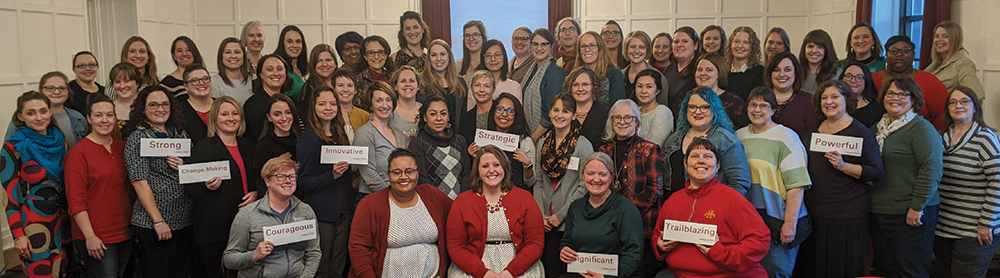 group photo of Cardinal Women holding signs reading strong, change-making, powerful, strategic, innovative, trailblazing, significant, and courageous